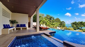 A modern pool area with blue-tiled edges, lounge chairs, and a view of the sea. - Villa Seven Swifts (Koh Samui)