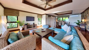 A spacious living room with wicker furniture, a coffee table, and a ceiling fan. - Villa Seven Swifts (Koh Samui)