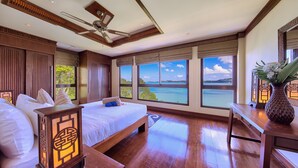 A hotel room with a large bed, a desk, and a view of the sea. - Villa Seven Swifts (Koh Samui)