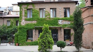 A hotel with a brick facade, ivy-covered walls, and a sign that reads "Hotel Villa." - Hotel Tiflis (Tbilisi)