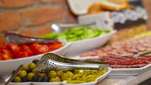 A buffet table with various food items including olives, tomatoes, green beans, and sliced meats. - Hotel Tiflis (Tbilisi)