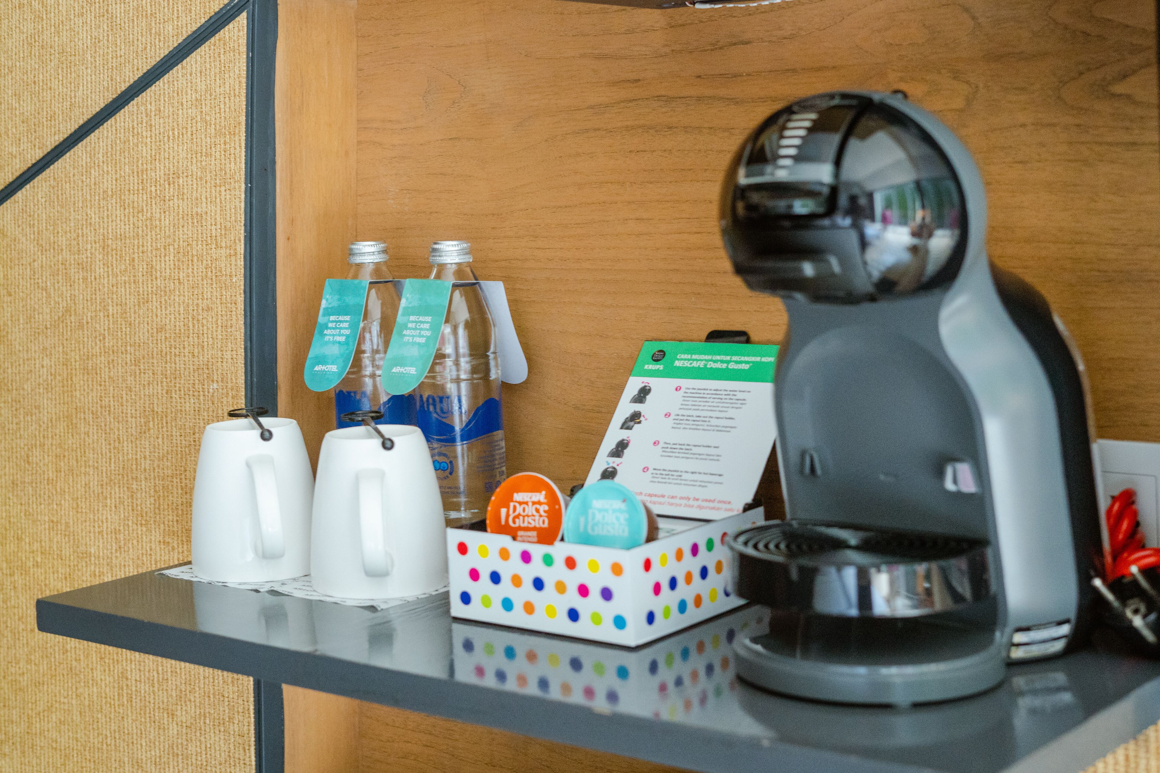 Une machine à café, deux tasses blanches, un récipient à pois et un menu posés sur un comptoir en bois.