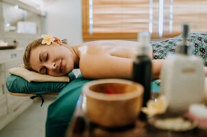 Una persona recostada en una camilla de masajes en un spa, con una mesa de madera al frente.
