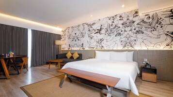 Ett modernt hotellrum med en stor säng, ett skrivbord, en soffa och en väggmålning.