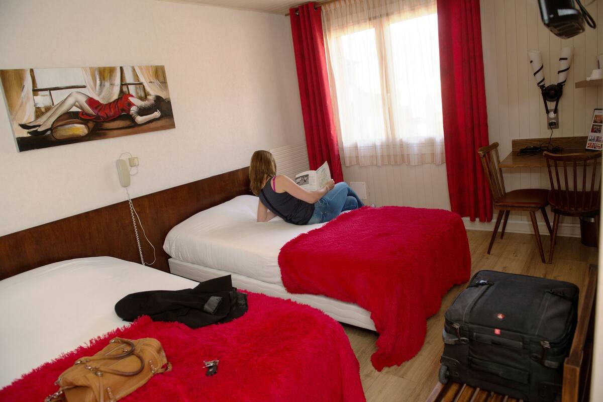 Habitación de hotel con dos camas, un escritorio y una silla.