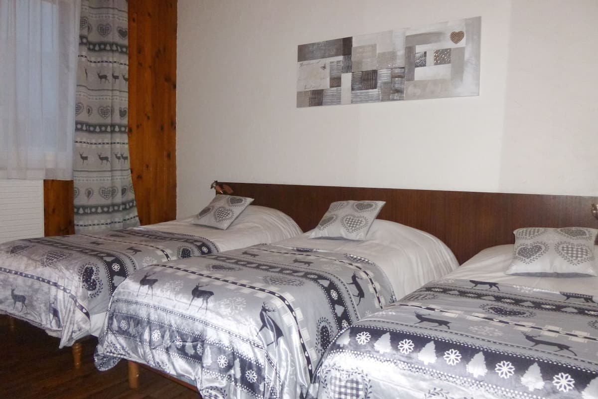 Habitación de hotel con dos camas, cada una con ropa de cama y almohadas estampadas, cabeceros de madera y una pared decorada con obras enmarcadas.