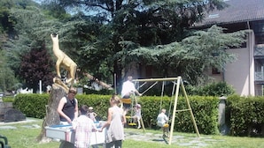 Un parque infantil con un columpio, una estatua y una mesa de picnic.