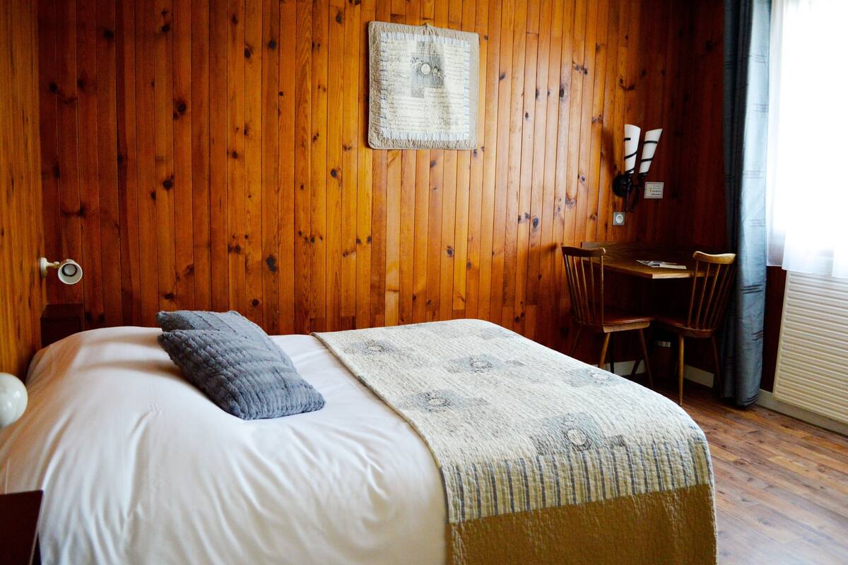 Habitación con paneles de madera, una cama, un escritorio y una silla.
