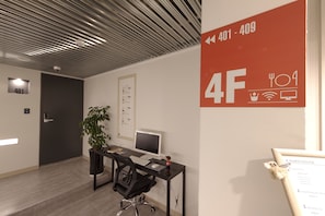 A modern office space with a desk, computer, and chair. A potted plant is on the desk. A sign indicates room numbers 401-409. - K-Grand Hotel Myeongdong (Seoul)