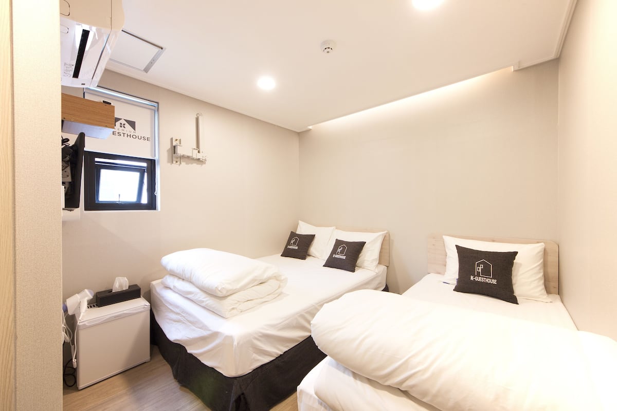 Une chambre d’hôtel avec deux lits, un petit bureau et une fenêtre.