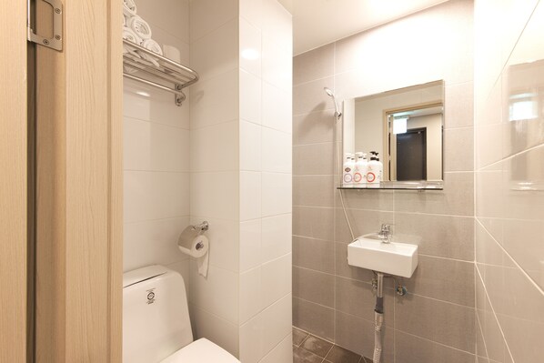 A bathroom with a toilet, a sink, a shower, and a towel rack.