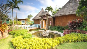 A traditional thatched-roof building with a small pond and a bridge. - Reewa Waree Resort (Pak Chong)