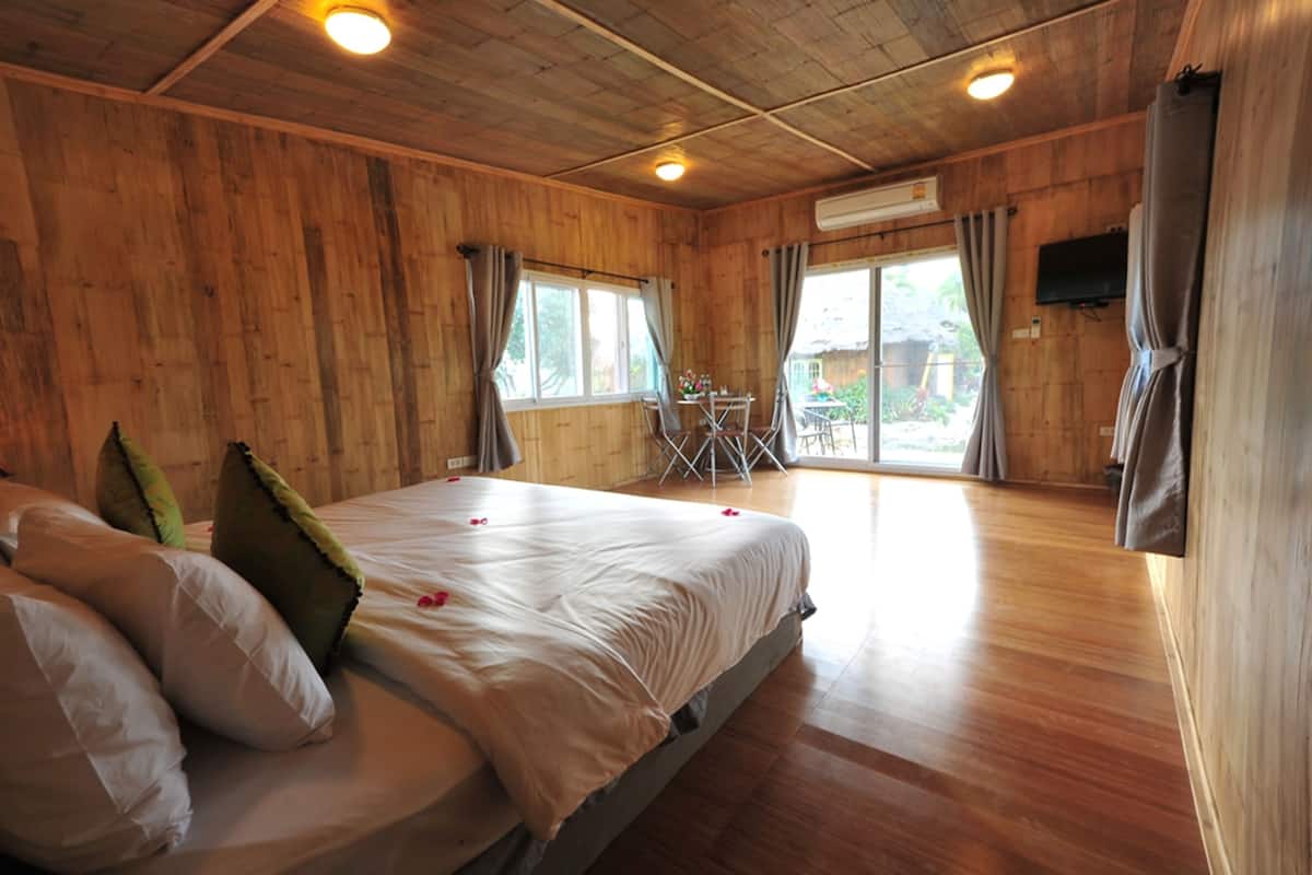 Une pièce en bois avec un lit, une table et un téléviseur.
