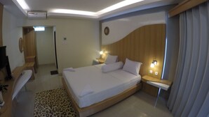 A modern hotel room with a large bed, bedside tables, a desk, and a shower area. - Coral Beach 2 Bungalow (Gili Trawangan)
