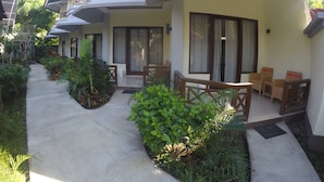 A hotel with a covered outdoor area, multiple rooms with balconies, and a pathway lined with greenery. - Coral Beach 2 Bungalow (Gili Trawangan)