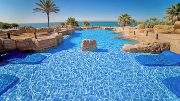Una piscina al aire libre, sombrillas, tumbonas