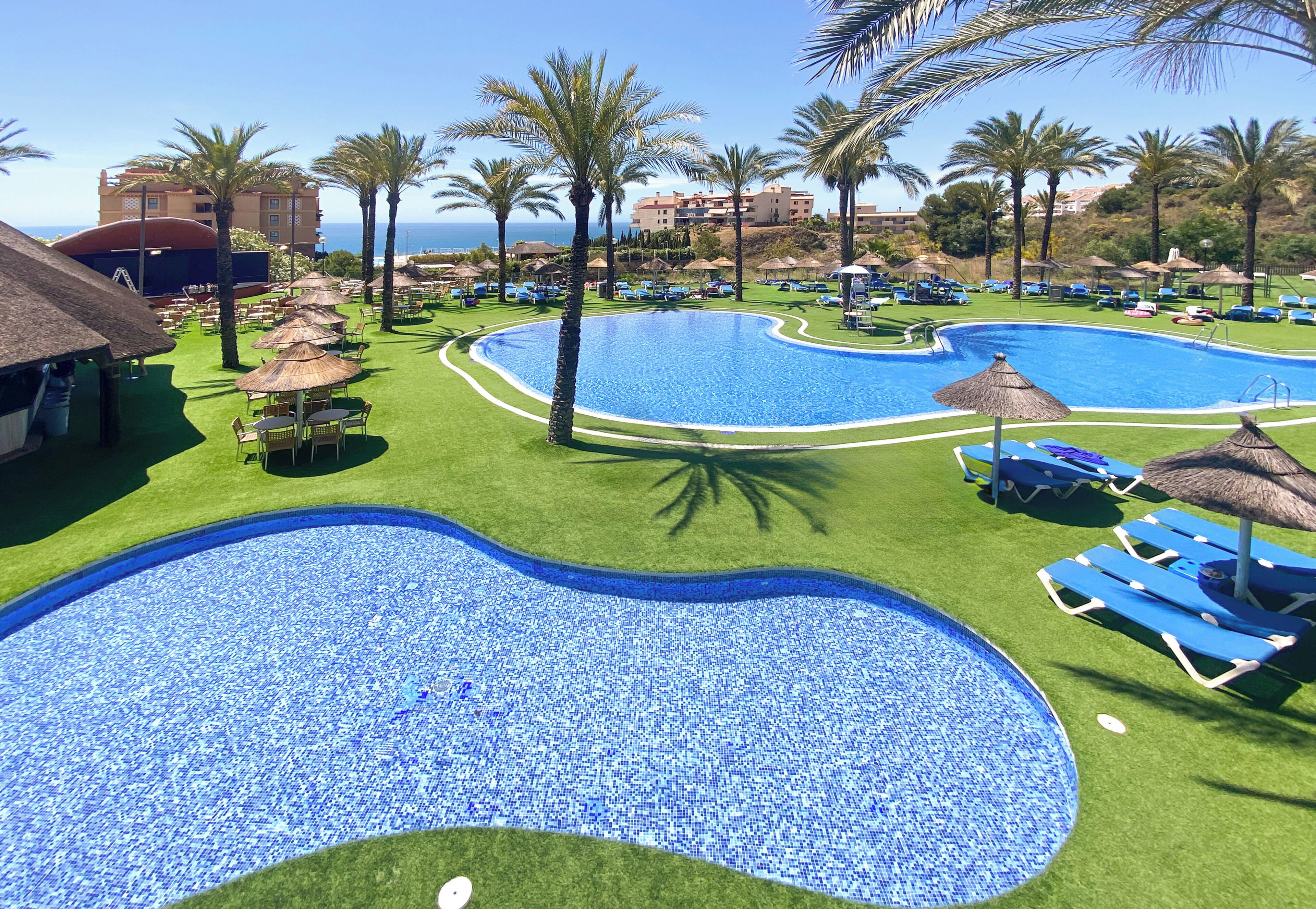 A resort pool area with multiple pools, palm trees, and lounge chairs.
