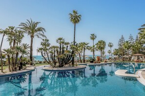 Una piscina al aire libre, sombrillas, sillones reclinables de piscina