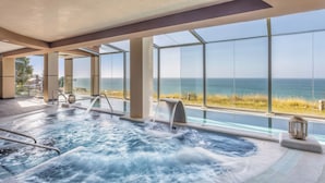 Een bubbelbad met uitzicht op de oceaan, grote ramen en een modern interieur.