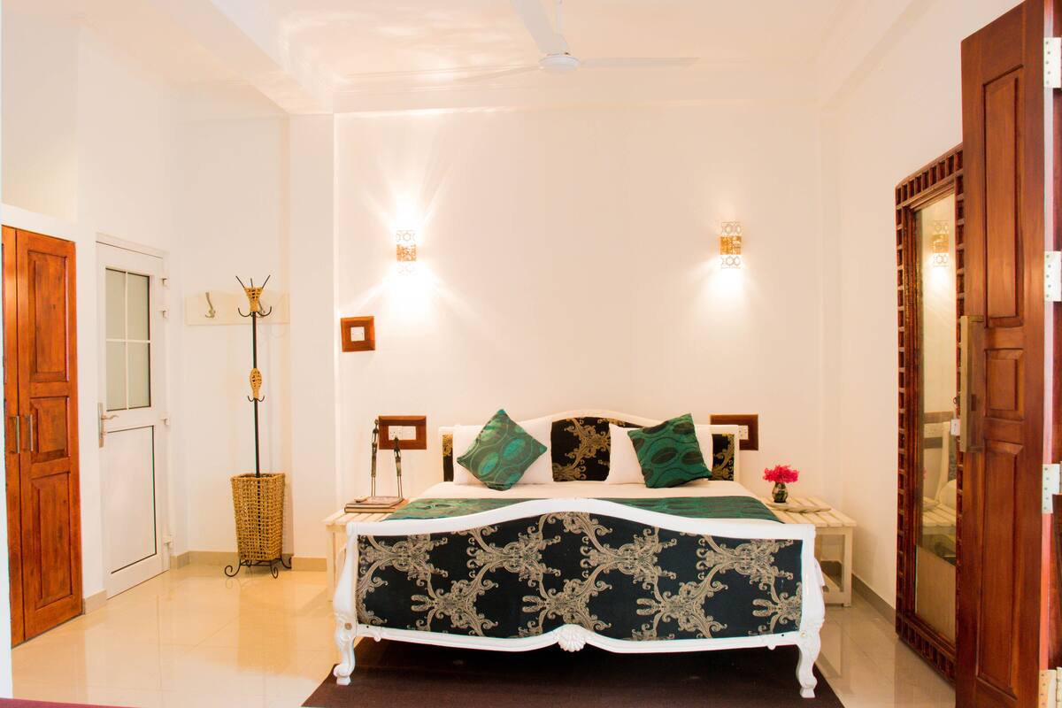 A bedroom with a bed, a standing lamp, and a door.