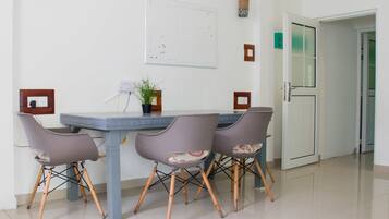 Un comedor con una mesa y cuatro sillas, una planta en maceta y una pizarra en la pared.