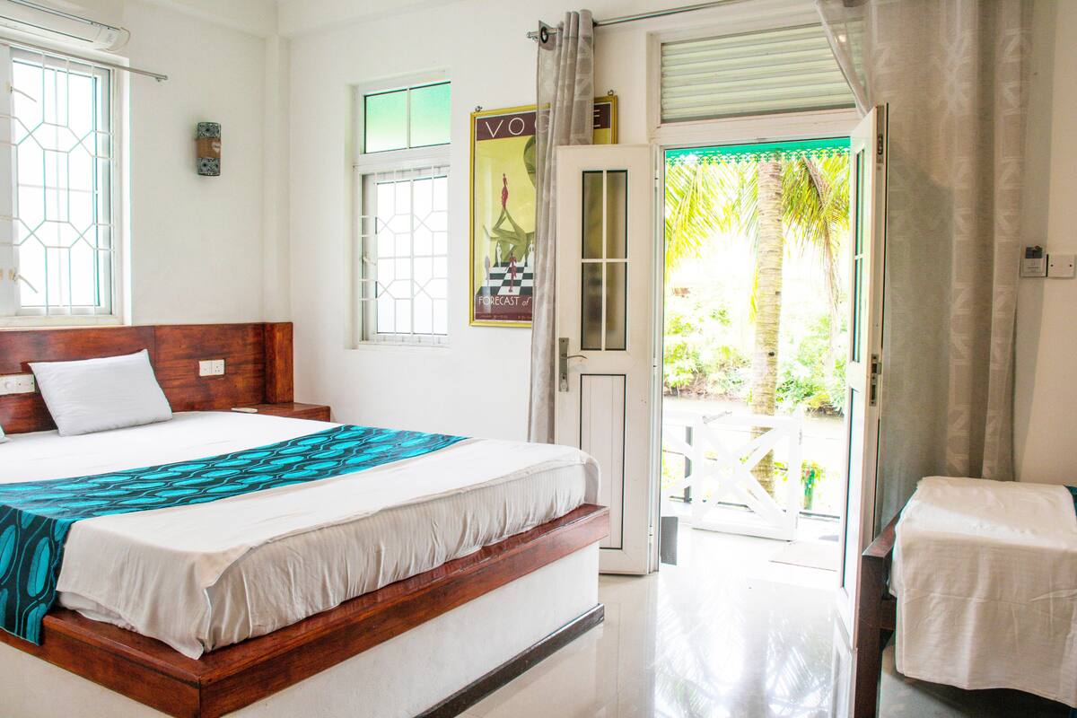 A hotel room with a bed, a window, a door, and a view of the outdoors.
