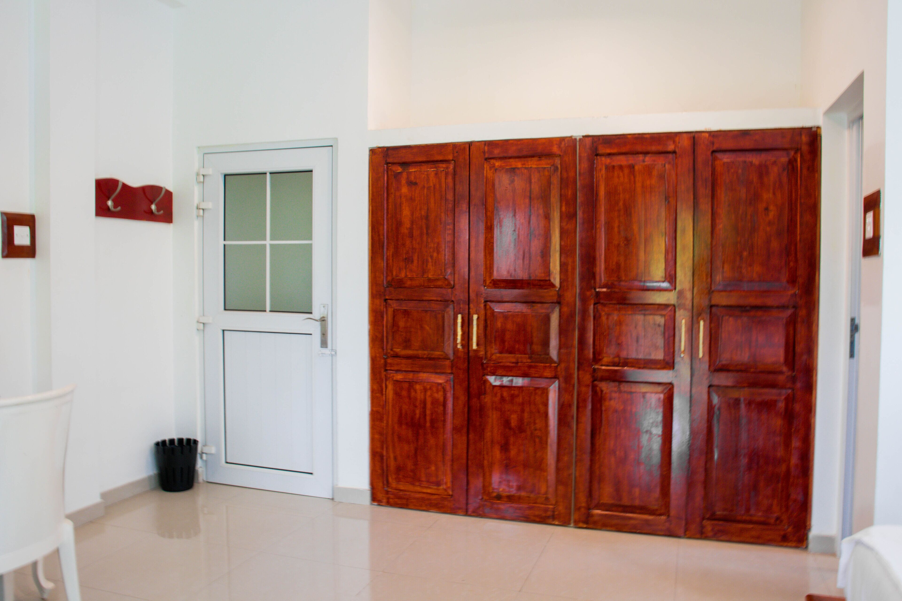 A hallway with a white door, a black trash bin, and a set of wooden double doors.