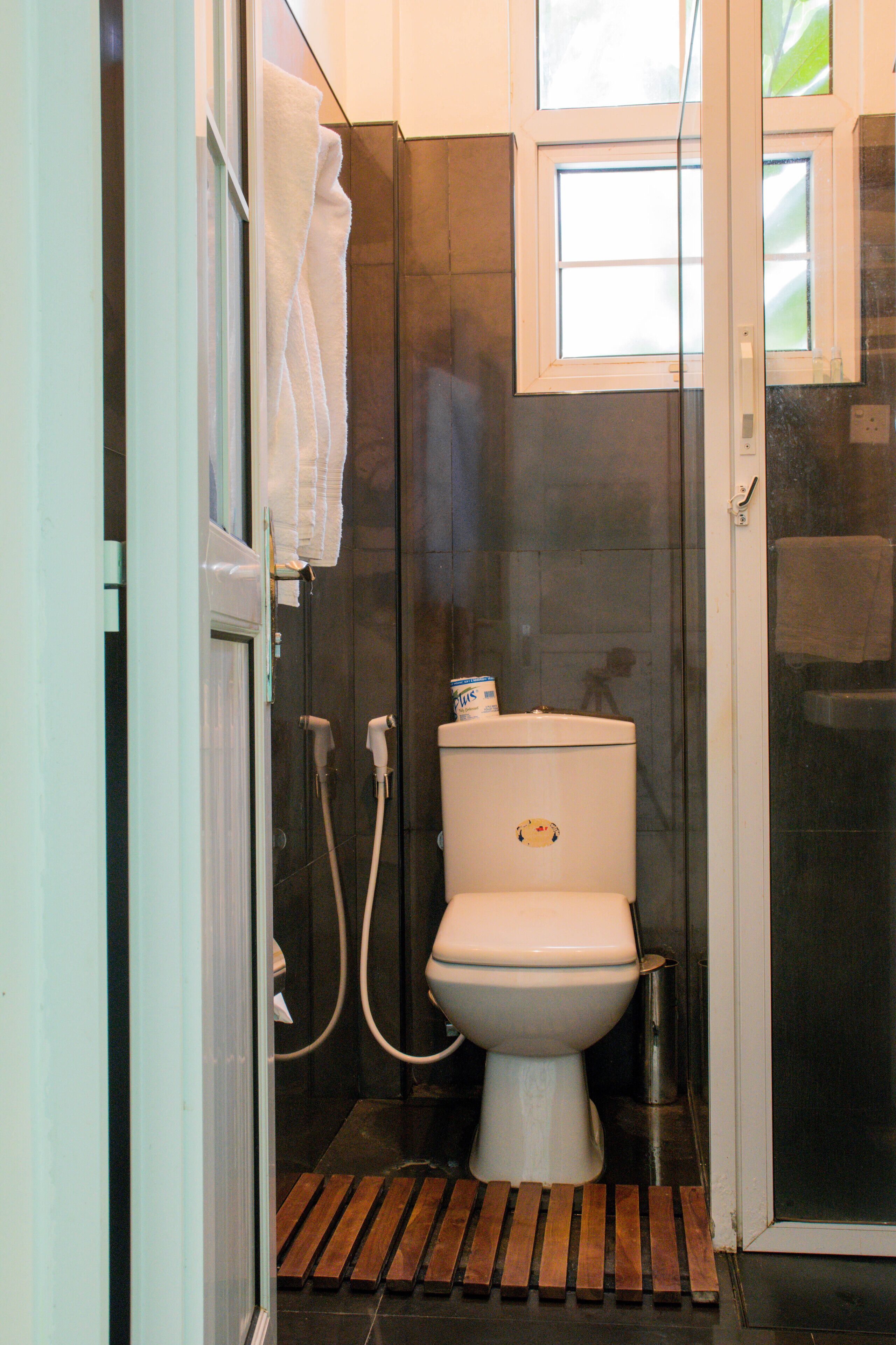Un baño pequeño con inodoro, cabina de ducha y un ventanal.