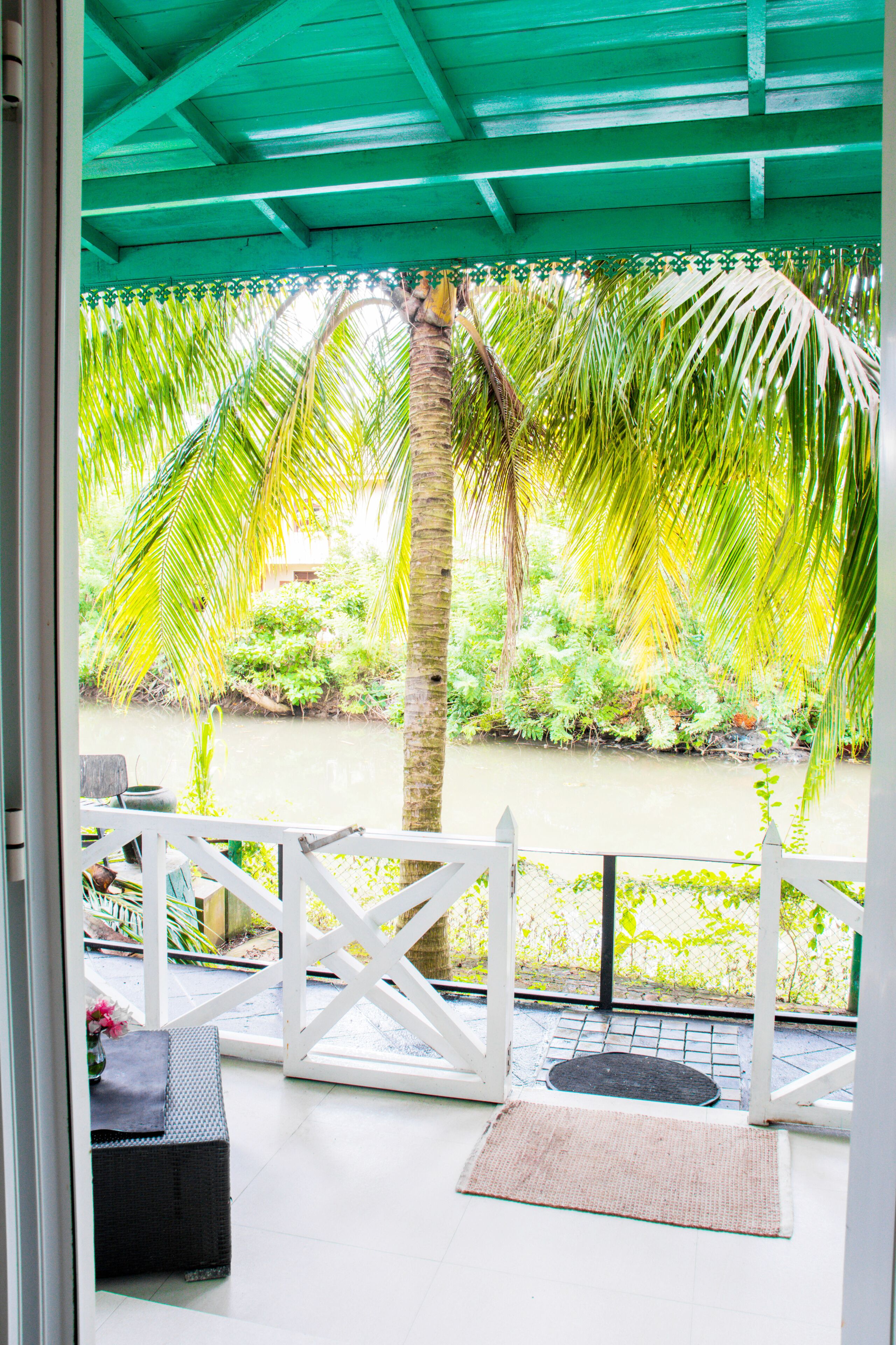A covered porch with a view of a river and greenery.