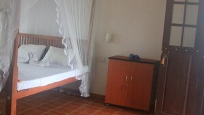 Une pièce avec un lit en bois, du linge de lit blanc, une armoire en bois et une porte avec une fenêtre.