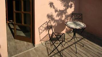 Un patio con tavolo e sedie di legno, una porta e un tetto in tegole.
