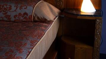 A bed with a patterned bedspread and a bedside lamp on a wooden nightstand.