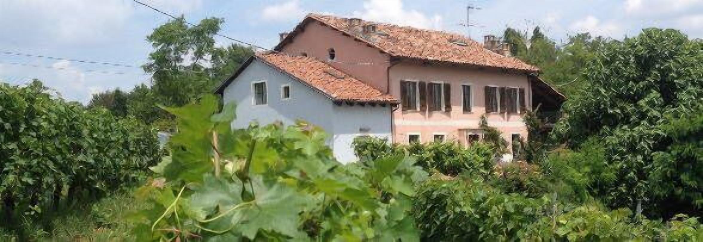 A two-story house with a tiled roof, surrounded by lush greenery.
