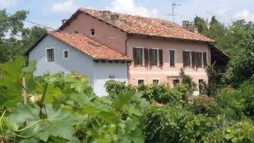 A two-story house with a tiled roof, surrounded by lush greenery.