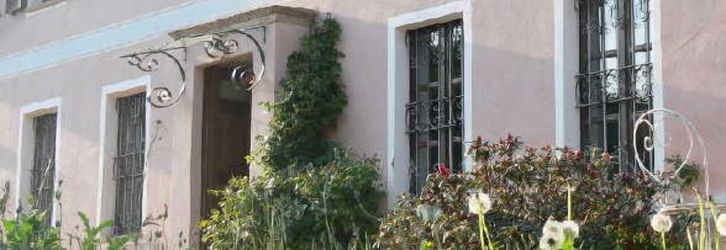 A building with large windows, a balcony, and some greenery.