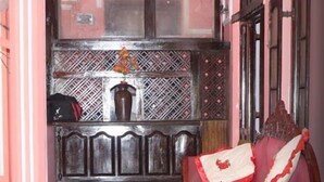 Ett traditionellt rum med en soffa i trä, ett litet runt bord och en dekorativ skärm.