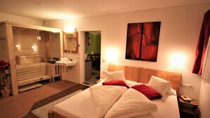 Une chambre d’hôtel avec un lit, une salle de bain, un miroir et un tableau au mur.