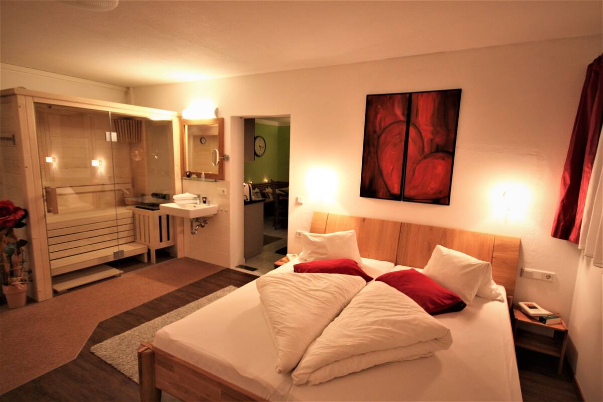 Una habitación de hotel con cama, baño, espejo y un cuadro en la pared.