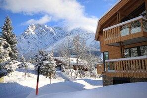 A wooden chalet with a balcony, surrounded by snow-covered trees and mountains in the background. - Mountain-Apart Simonhof (Maria Alm am Steinernen Meer)
