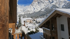 Un bâtiment en bois doté d’un balcon, avec une montagne enneigée en arrière-plan et un ciel dégagé.