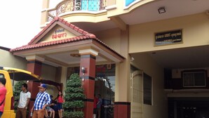 A hotel entrance with a tiled roof, a signboard, and a potted plant. - Khemra I Guesthouse (Kampot)