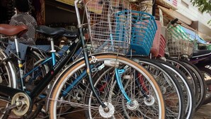 A row of bicycles parked on a sidewalk with baskets attached to the front. - Khemra I Guesthouse (Kampot)