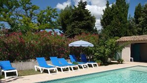 Une piscine avec des chaises longues bleues et un parasol blanc.