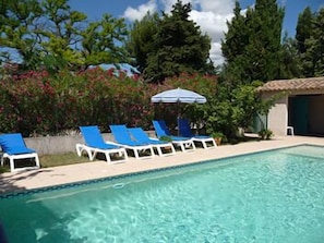 Een buitenzwembad en ligstoelen