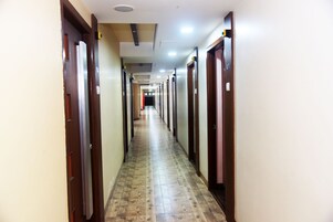 A long, narrow hallway with wooden doors on both sides, leading to individual rooms.