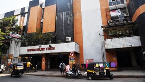 A multi-story building with a sign for 'Sampada Railway Station' and a 'Hotel Indiana Inn' sign. - Hotel Indiana Inn (Navi Mumbai)