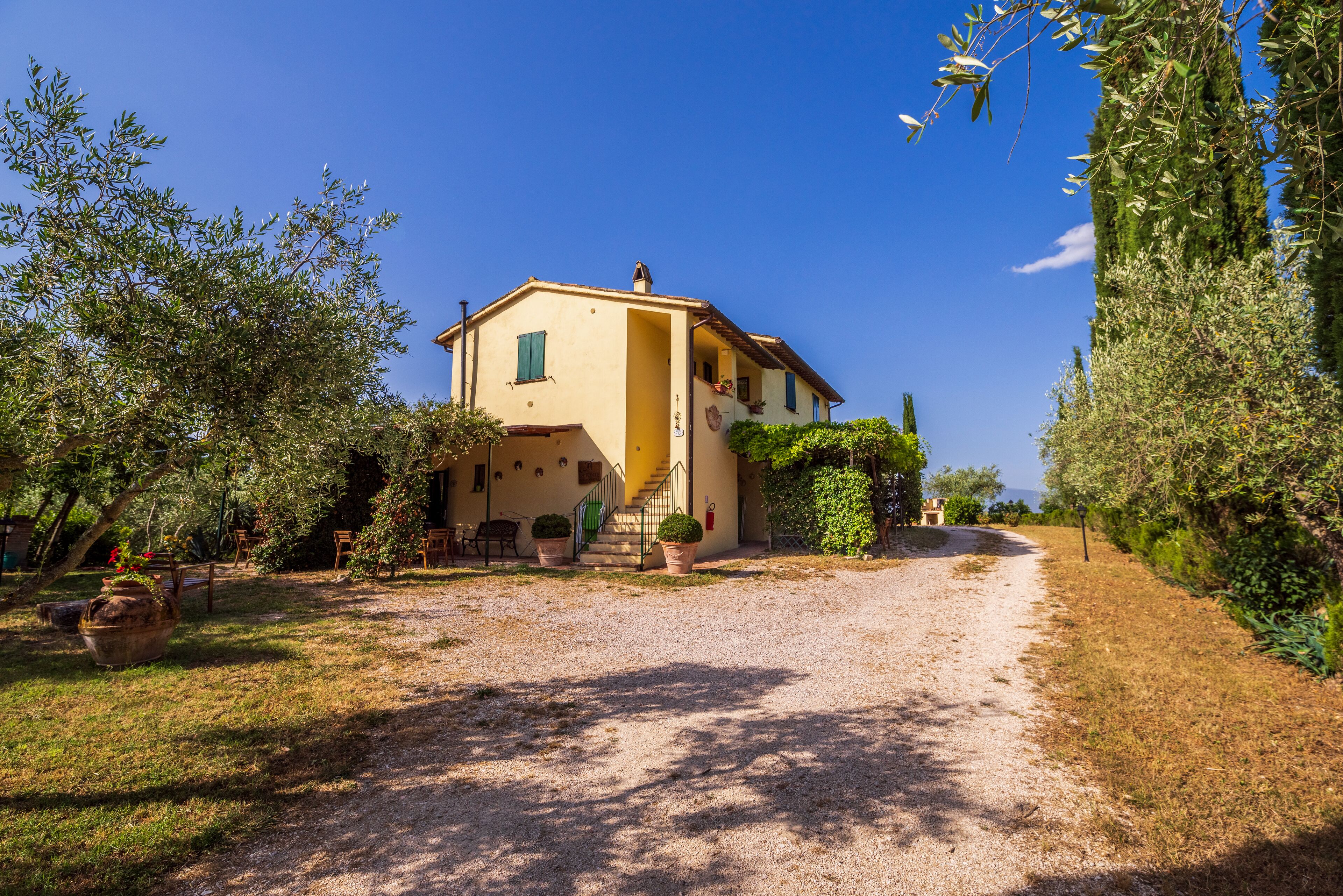 A two-story house with a gravel driveway leading to a front door.