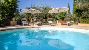 A swimming pool with lounge chairs and umbrellas, surrounded by trees and a clear sky. - Agriturismo La Fonte (Bevagna)