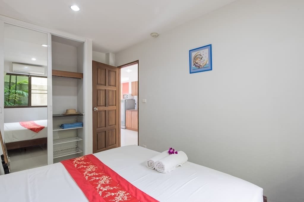 A hotel room with a bed, a wardrobe, a bathroom visible through an open door, and a framed picture on the wall.