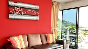 Un soggiorno moderno con un divano in pelle marrone, un tavolino da caffè in vetro e un quadro astratto rosso sulla parete.